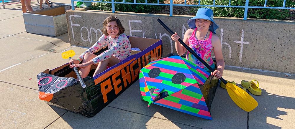 two girls in their cardboard boats ready to compete in the cardboard race