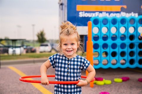 little girl at the sioux falls parks and rec mobile unit hula hooping and smiling at the camera