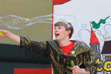 actors in costume on stage blowing bubbles