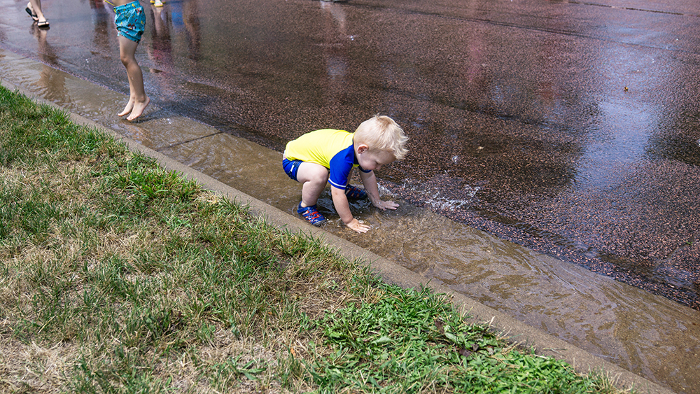 Toddler playing in a puddle at the hydrant party