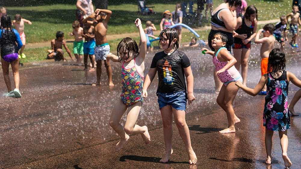 Children jumping in the water and having fun at the hydrant block party