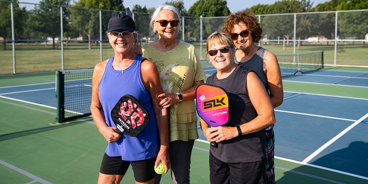 Women playing pickleball smiling at the camera