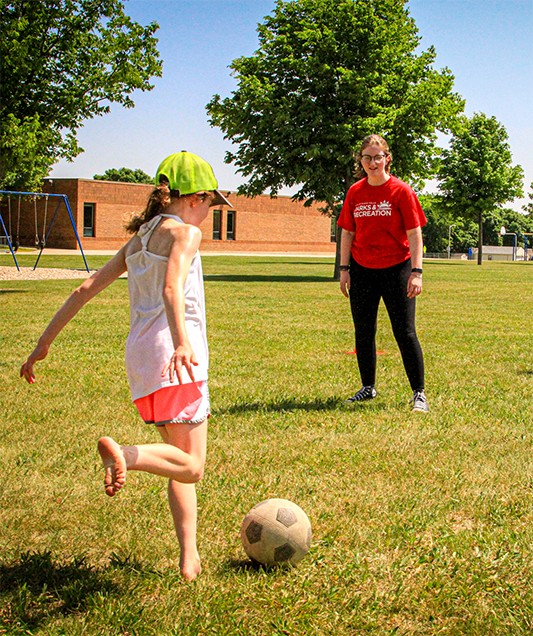 parks employee playing soccer with child