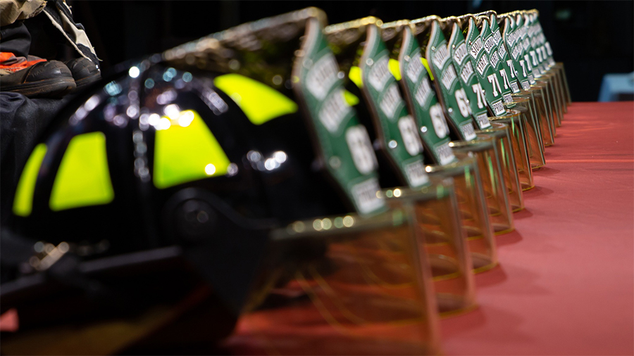 A row of firefighter helmets and gear meticulously arranged on a long table, likely at a firefighter training event or graduation ceremony.